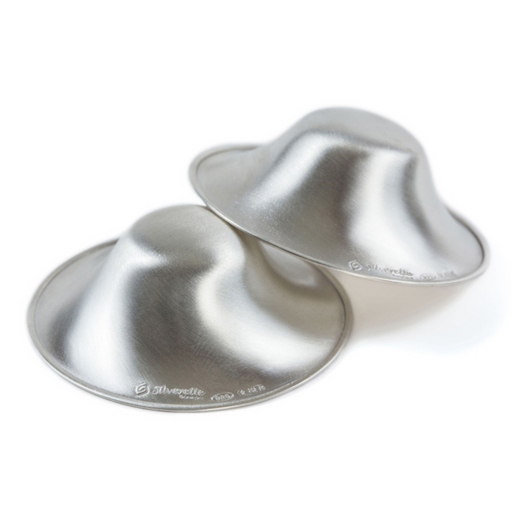 An image showcasing the Silverette Nursing Cups, a pair of small, round cups made of polished silver, sitting on a white surface. The cups have a shiny and elegant appearance, and their slightly curved shape is designed to fit comfortably over the nipple. 