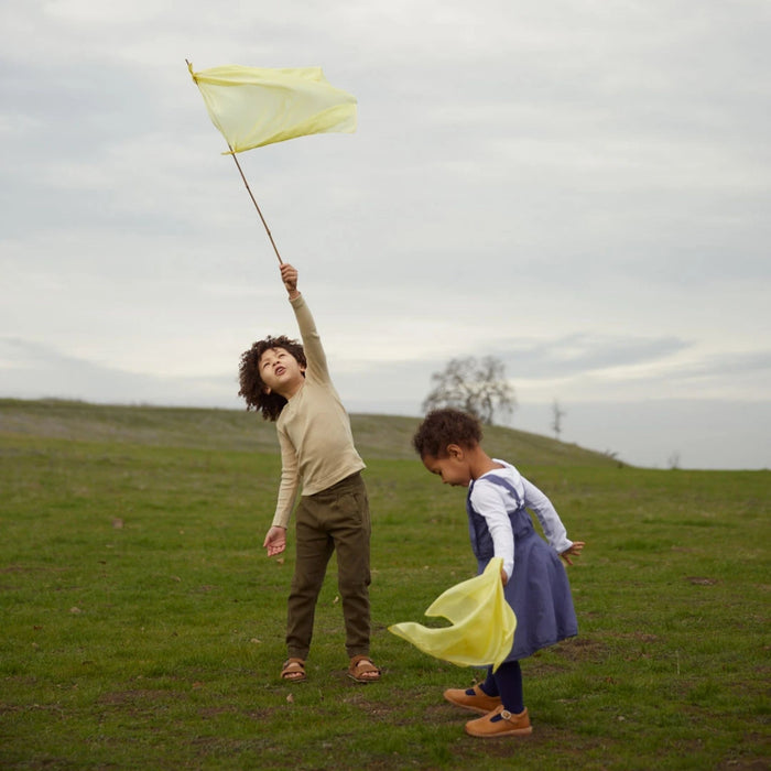 sarah's silks mini playsilks two kids play with light yellow mini playsilks in a field